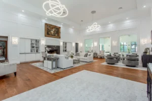 Luxurious living room in Waxahachie dream home with hardwood floors, crystal chandelier, elegant furnishings, and floor-to-ceiling windows overlooking the climate-controlled indoor pool—designed for sophisticated entertaining.