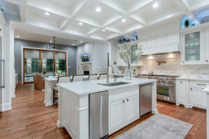 Bright gourmet kitchen in Waxahachie luxury home with custom cabinetry, large island, premium stainless steel appliances, marble backsplash, hardwood floors, and open concept layout for culinary excellence and entertaining.