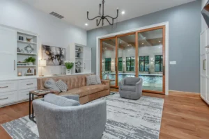 Elegant living area off kitchen in Waxahachie luxury home featuring expansive slider doors opening to the indoor pool, hardwood floors, and seamless flow—ideal for entertaining and extended culinary space.