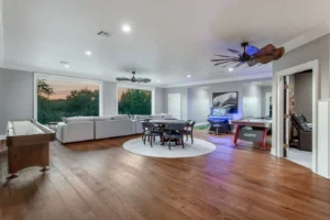 Expansive game room in Waxahachie residence featuring arcade video games, air hockey, shuffleboard, poker table, and spacious lounge area for entertainment and memorable social gatherings.