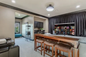 Modern home theater in Waxahachie estate with plush reclining seating, built-in bar, popcorn machine, large screen, and blackout curtains for immersive cinematic entertainment experiences.